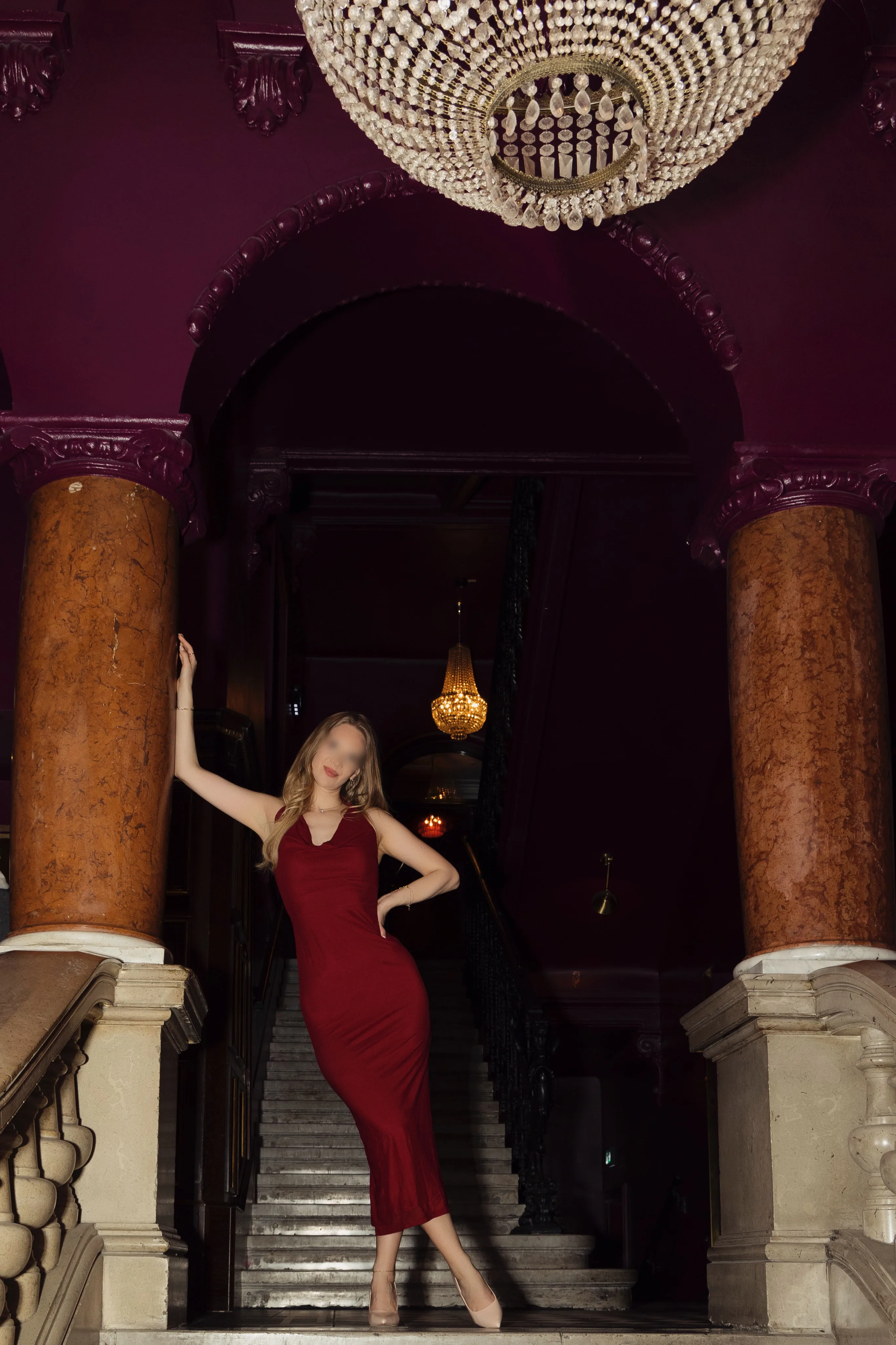 Hotwife Mara in red dress posing on luxury hotel staircase - vixen confidence and sensuality